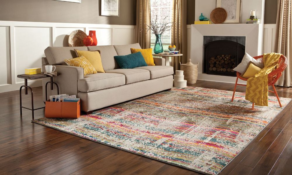 Large patterned rug anchoring a beige sofa and accent chair in a cozy living room with wooden floors.