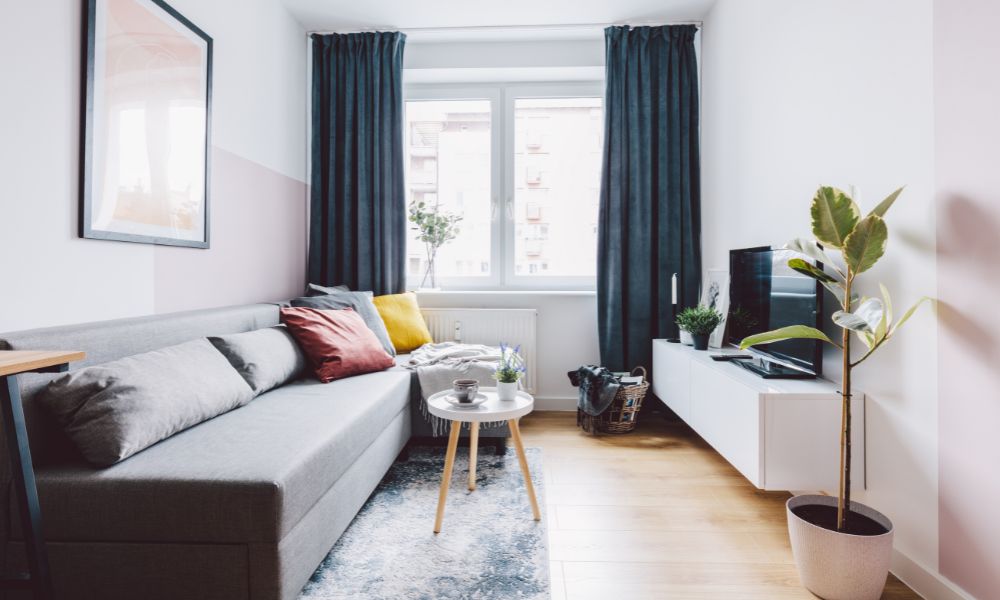 Small living room with a gray sofa positioned along the wall, facing a TV, with a compact coffee table and clear floor space.